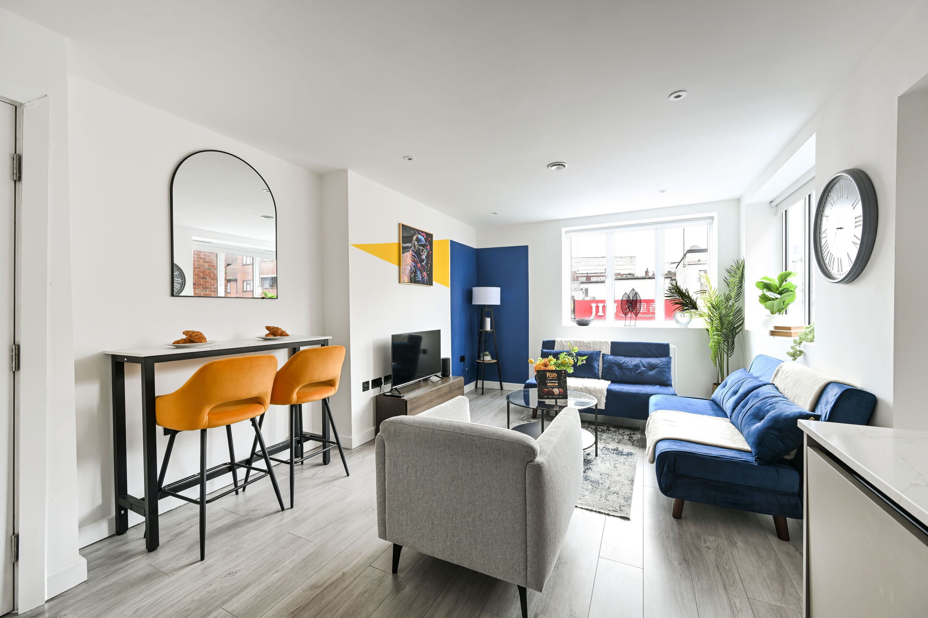 A modern living space with a dining area, a sofa, and a television.