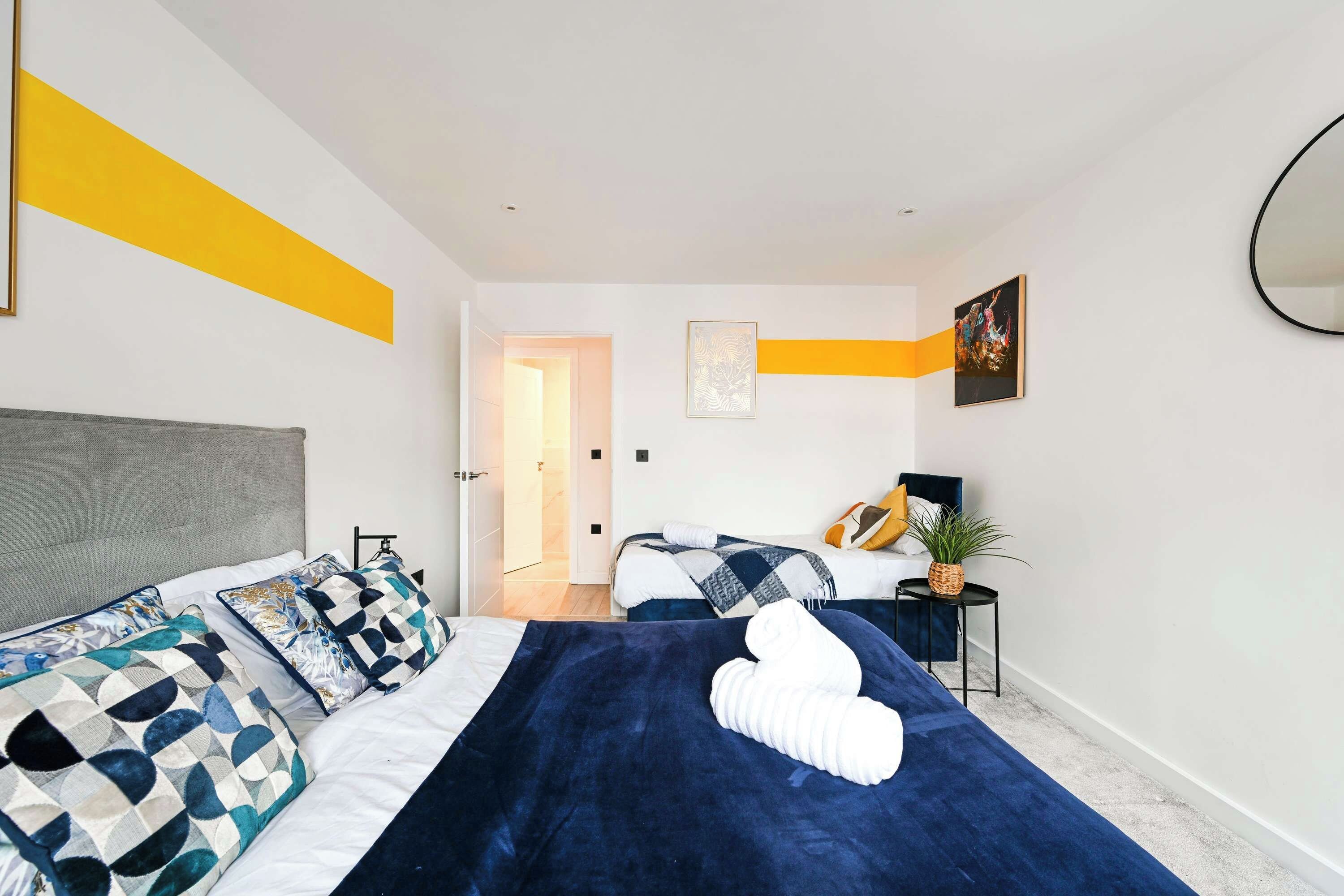 A modern bedroom with a large bed, a bedside table, a chair, and a mirror on the wall.