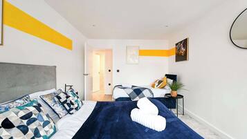A modern bedroom with a large bed, a bedside table, a chair, and a mirror on the wall.