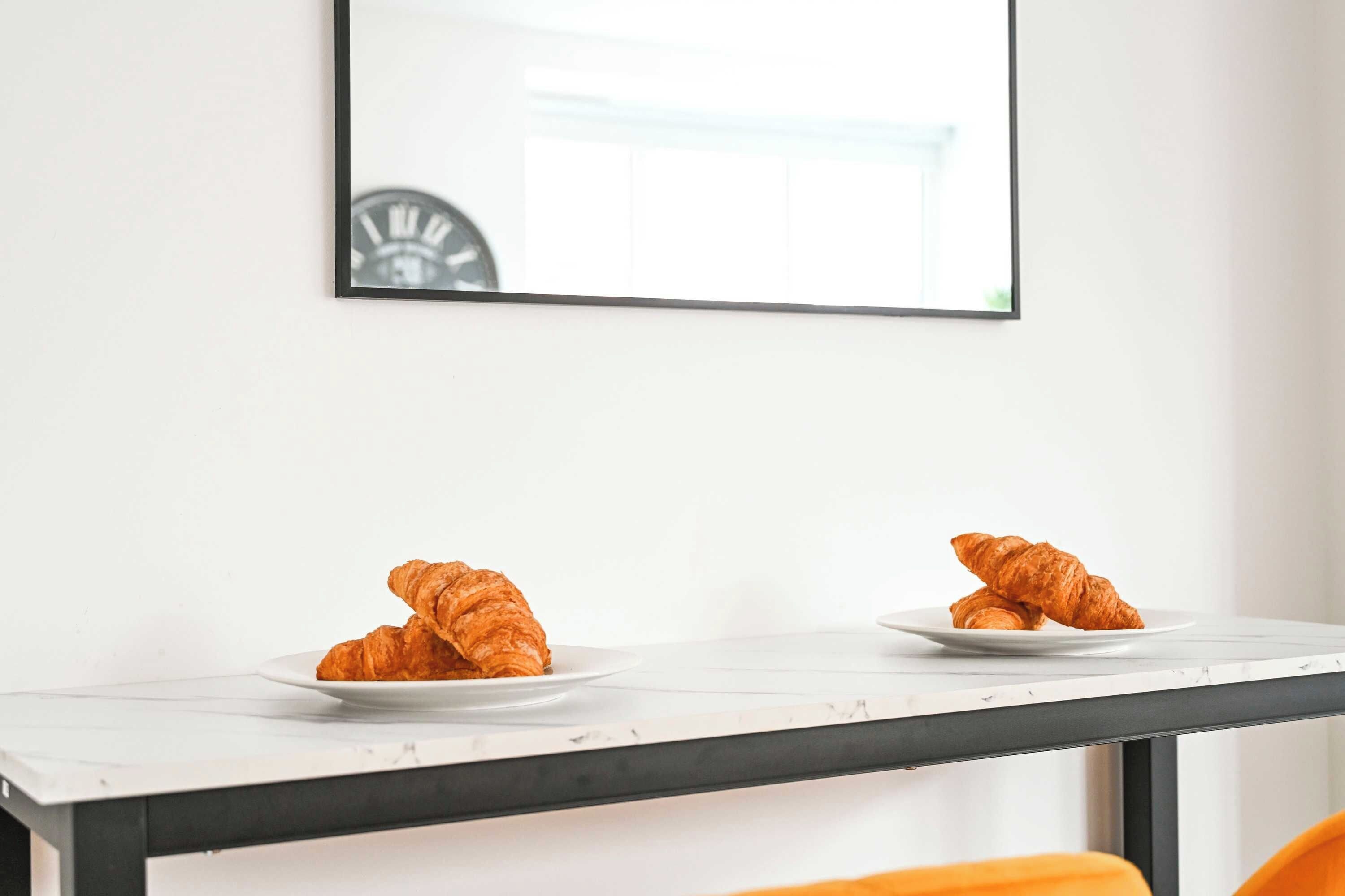 A white table with two plates of croissants.
