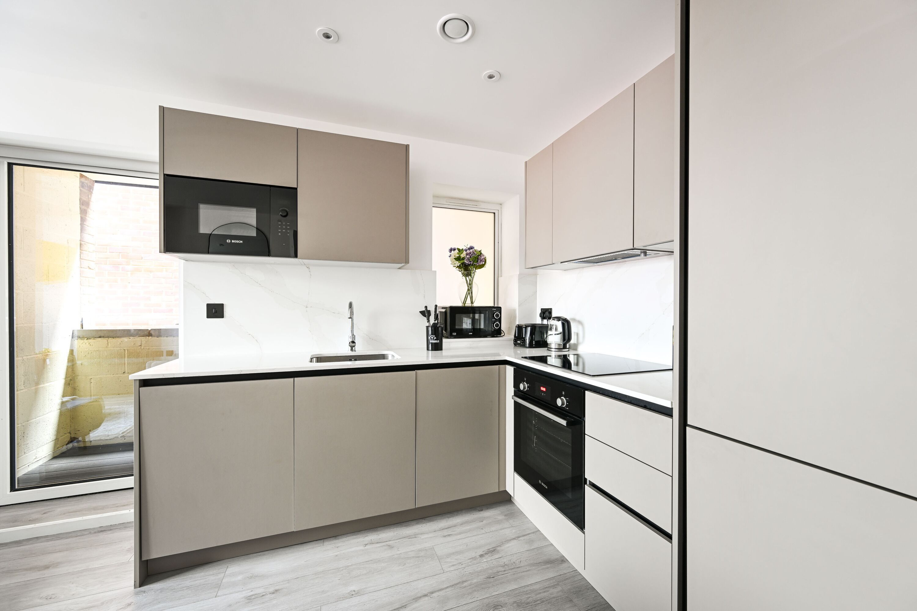 A modern kitchen with a central island, built-in appliances, and a large window.