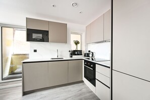 A modern kitchen with a central island, built-in appliances, and a large window. - Hendon flat, ideal for contractors, sleeps 6! (London)