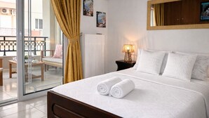 A hotel room with a bed, a nightstand, a lamp, a window with curtains, and a view of the outside balcony. - BH1041 - A - Summer Home (Agios Nikolaos)