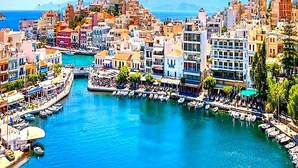 A coastal cityscape with a marina, buildings, and a clear blue sea. - BH1041 - A - Summer Home (Agios Nikolaos)