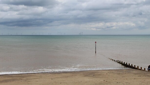 A beach with a wooden jetty extending into the water, a cloudy sky, and wind turbines in the distance. - Charming BnB Retreat in East Riding of Yorkshire (East Riding of Yorkshire)