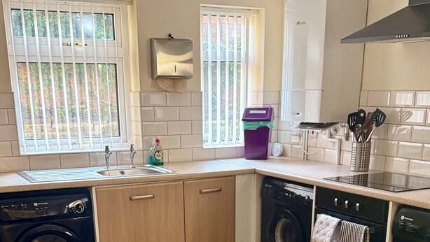 A kitchen with a washing machine, a dishwasher, and a countertop with a soap dispenser. - Spacious House Sleeps 10 -Near BikePark Wales -Central -Parking (Troedyrhiw)