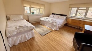 A bedroom with two beds, a desk, a chair, and large windows. - Spacious House Sleeps 10 -Near BikePark Wales -Central -Parking (Troedyrhiw)