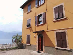 Un bâtiment à deux étages, doté de nombreuses fenêtres, d’une porte rouge et d’une entrée pavée de pierres.