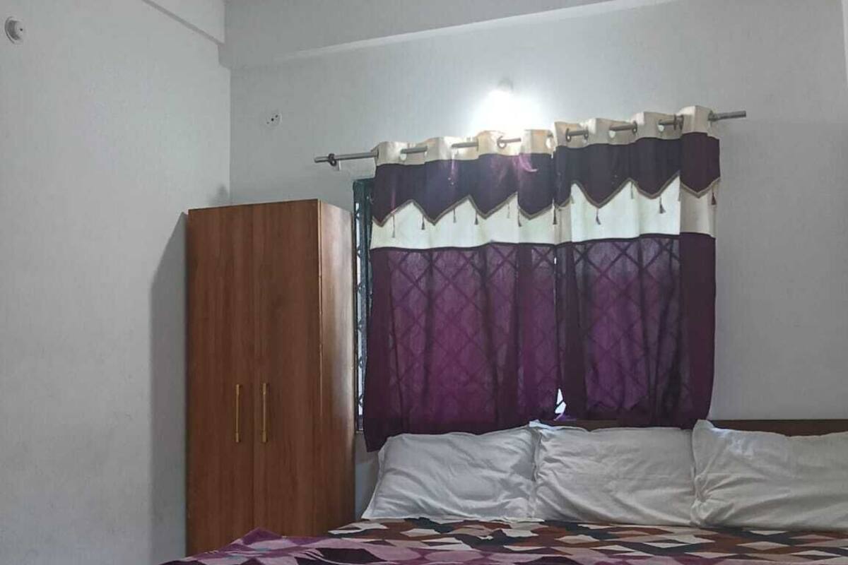 Un dormitorio con cama, ventilador de techo, armario y ventana con cortinas moradas.