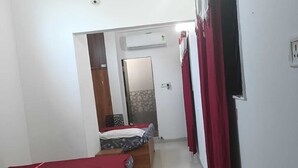 Een hotelkamer met twee enkele bedden, een garderobe, een spiegel en een deur naar een andere kamer.