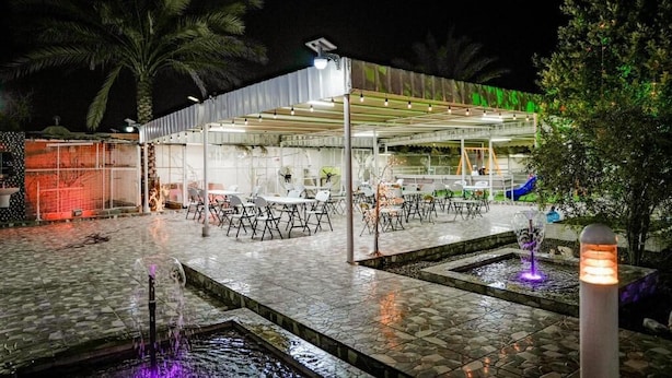 An outdoor dining area with tables and chairs, a covered seating area, and a water feature.