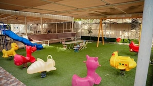 A children's play area with a slide, swings, and animal-shaped play equipment.