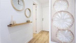 A hallway with a wooden shelf, two wall-mounted mirrors, and a door. - Vv03. Atardecer Martianez (Puerto de la Cruz)