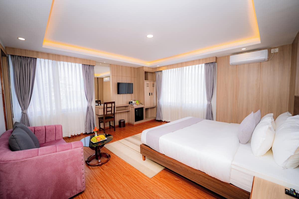 Una habitación de hotel con cama, escritorio, silla y sofá.