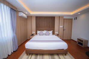 Een moderne hotelkamer met een groot bed, houten paneelbekleding, een nachtkastje en een ingebouwde kledingkast.