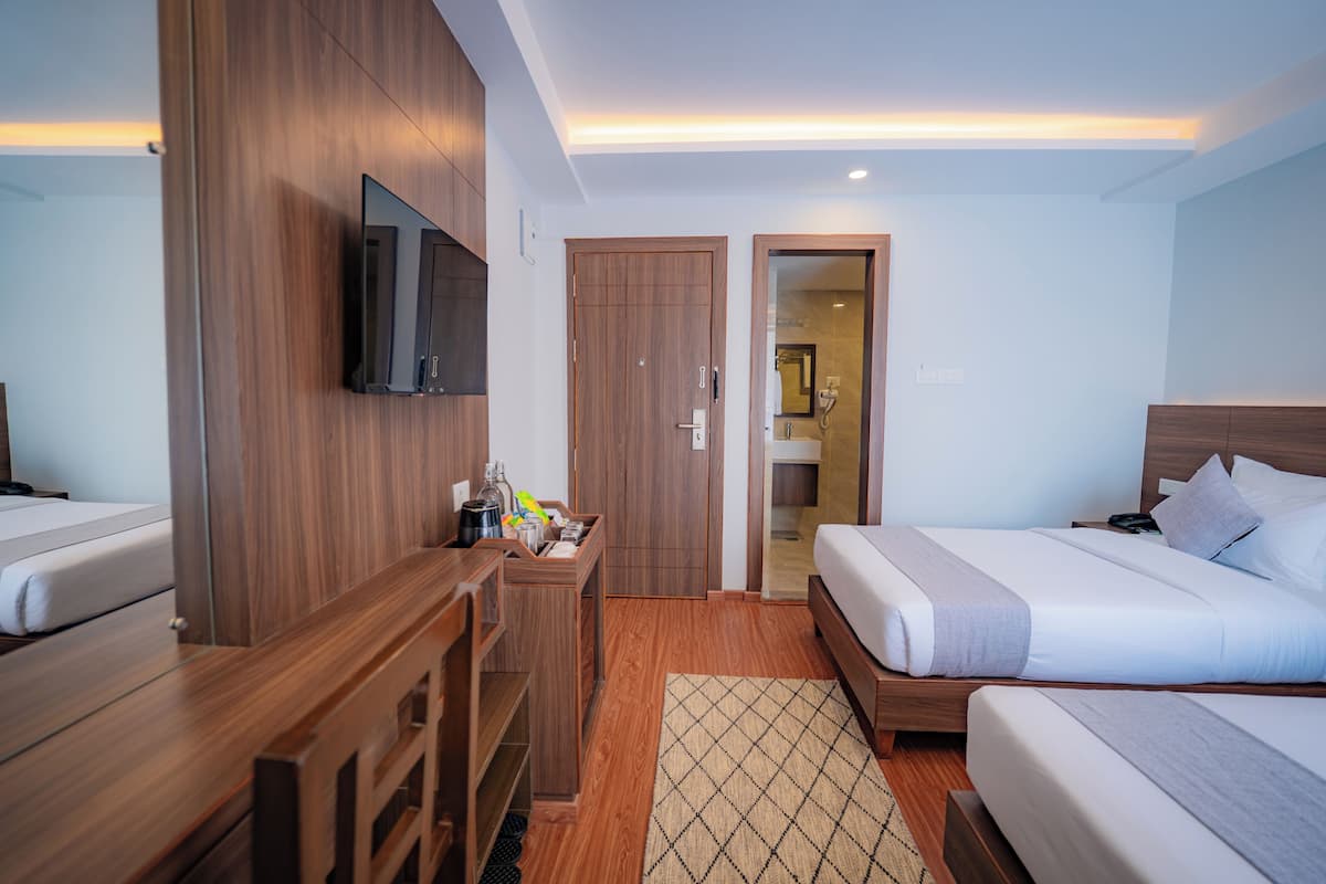 Una habitación de hotel con dos camas, televisi ón, armario de madera y escritorio con hervidor.
