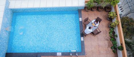 A rooftop pool with a 'No Diving' sign, surrounded by potted plants and a seating area.
