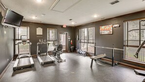 Ein Fitnessraum mit Laufbändern, Crosstrainern und einer Bank.