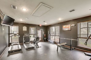 Un gimnasio con cintas de correr, elípticas y un banco.