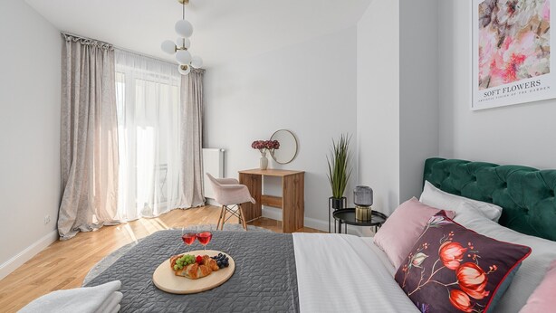 A bedroom with a bed, a bedside table, a chair, a desk, a window with curtains, and a wall art piece. - Lumina stylish apart Park Skaryszewski (Warsaw)