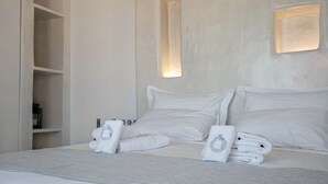 A hotel room with a bed, pillows, and towels. - Villa "Pasithoe" with Private Terrace, Wi-Fi and Air Conditioning (Koufonisi)