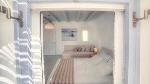 Un dormitorio con cama, sofá, un cuadro en la pared y una puerta.