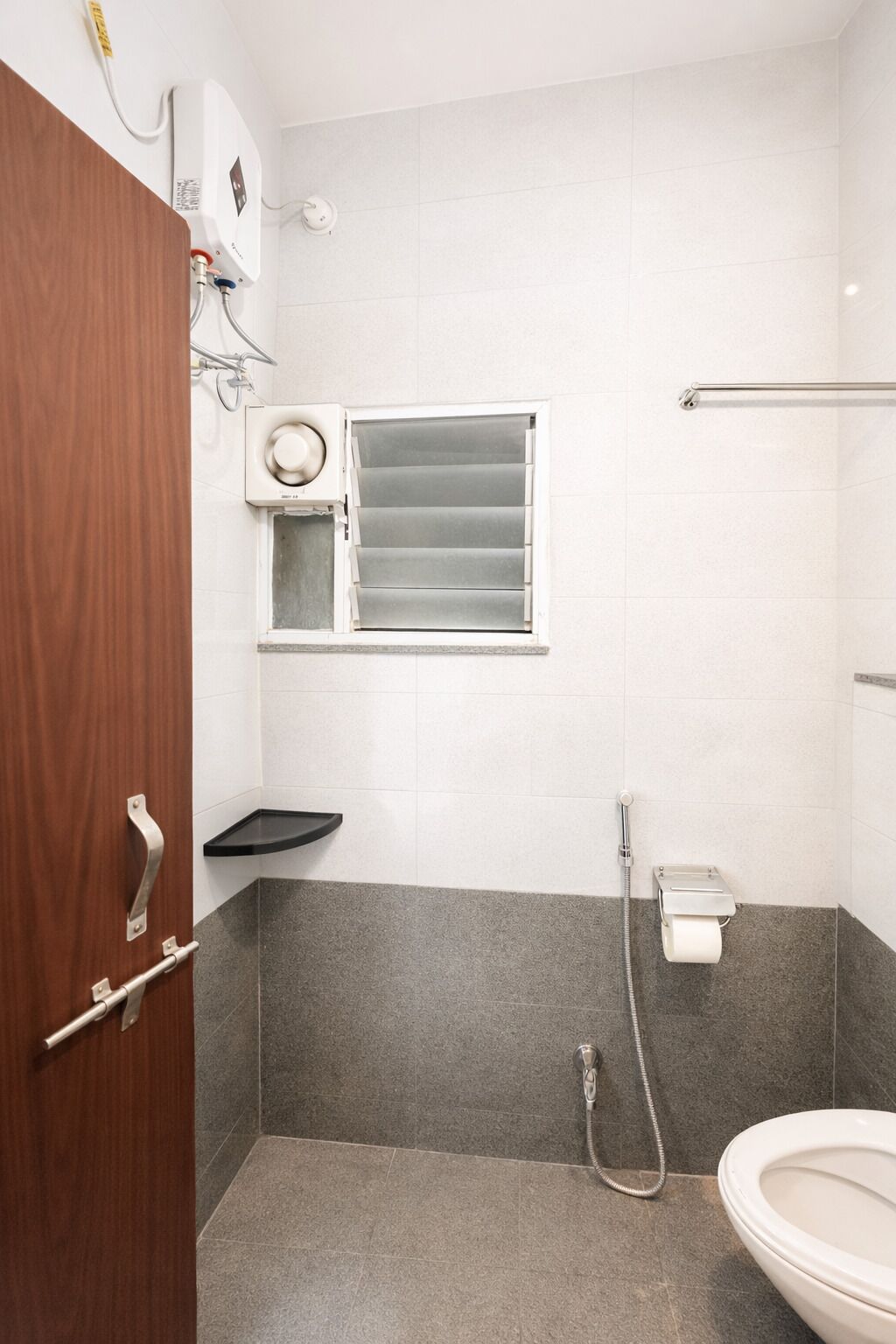 Ein Badezimmer mit Dusche, Toilette und einem Fenster mit Jalousien.
