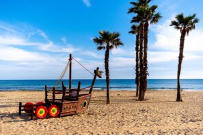 A beach with a wooden boat, palm trees, and the ocean. - BlueCalp: Just 2 minutes from the beach and the boardwalk—Modern living in a prime location in Calp (Calp)