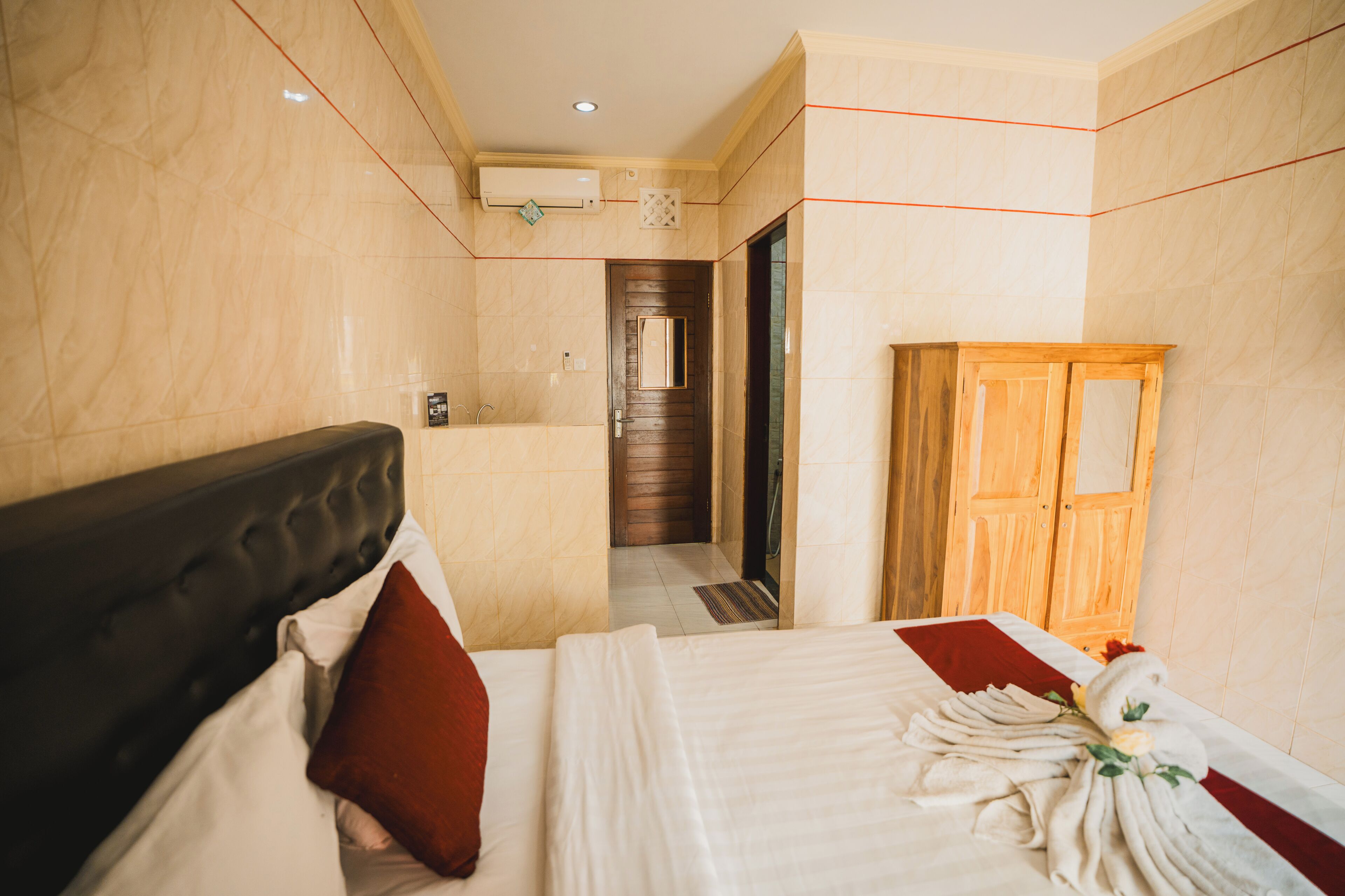 A hotel room with a bed, a wooden wardrobe, a bathroom, and a shower area.