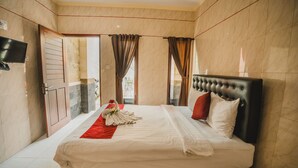 Una habitación de hotel con cama, cortinas, un televisor de pantalla plana y una puerta.