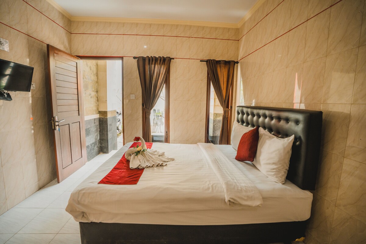A hotel room with a bed, curtains, a flat-screen TV, and a door.