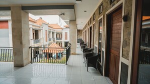 Un espacio al aire libre cubierto con piso de baldosas, barandilla y una fila de sillas.