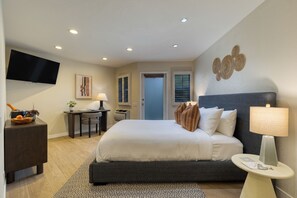 A hotel room with a large bed, a desk, a flat-screen TV, and a door leading to another room. - 1 Block to Beach | Pool + Hot Tub + Rooftop Terrace | The Mara by AvantStay (Laguna Beach)