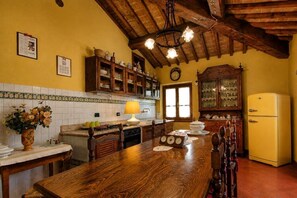 Una cocina con armarios de madera, un refrigerador amarillo y una mesa de comedor de madera.