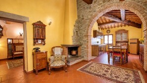 Un interior rústico con chimenea de piedra, muebles de madera y suelo de baldosas.