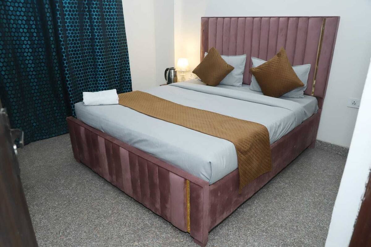 A single bed with a headboard, a bedside table with a lamp, and a curtain.