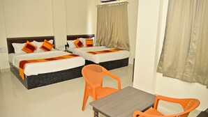 Hotellihuone, jossa on kaksi sänkyä, pöytä ja oranssi tuoli.