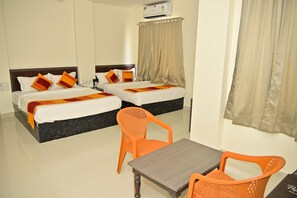 Une chambre d’hôtel avec deux lits, une table et une chaise orange.