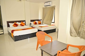 A hotel room with two beds, a table, and a chair. - Papaya Leaf Resort Nathdwara (Nathdwara)