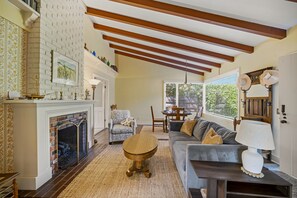 Ein Wohnzimmer mit Kamin, einer Couch, einem Esstisch und einer Deckenleuchte.