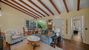 Ein Wohnzimmer mit Sofa, Sessel, Esstisch und einem großen Fenster.