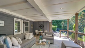 A covered porch with a sofa, chairs, a coffee table, and a dining table. - Boat Dock + Yard: Lake Lanier Gem in Gainesville (Gainesville)