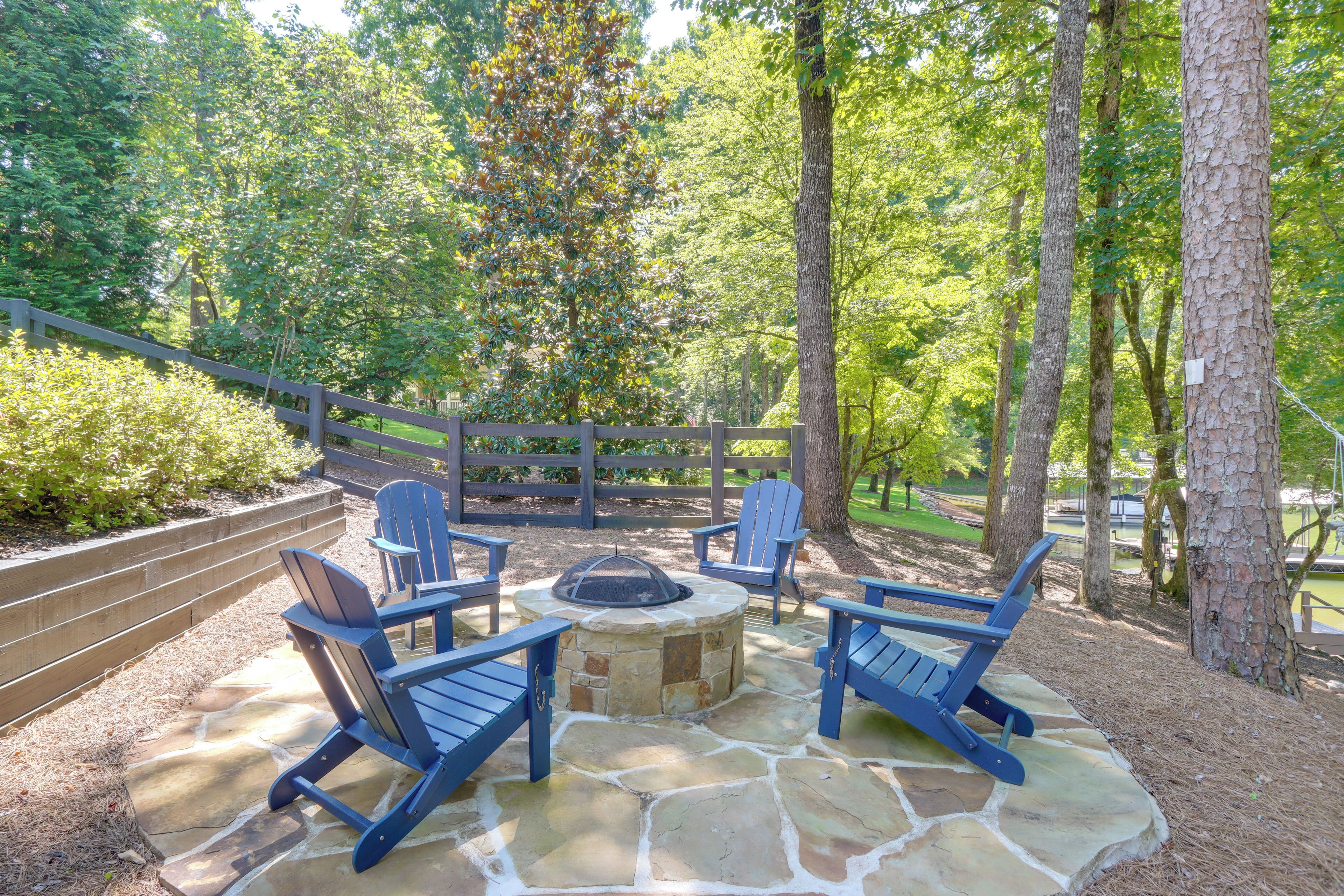 An outdoor seating area with stone flooring, surrounded by a wooden fence and trees.