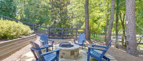 An outdoor seating area with stone flooring, surrounded by a wooden fence and trees.