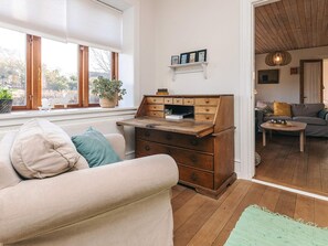 A cozy living room with a wooden chest of drawers, a sofa with cushions, a small table, and a view through an open door to another room. - 8 Person Holiday Home in Rudkobing (Rudkobing)
