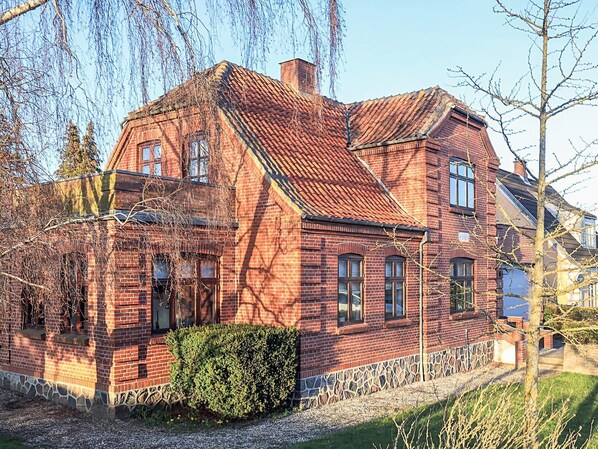 A red brick house with a stone foundation, multiple windows, and a chimney.