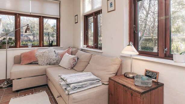 A cozy room with a sofa, a lamp, and a window with a view of trees.