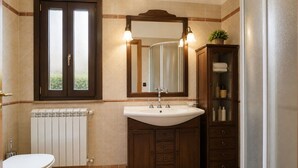 Une salle de bain avec des toilettes blanches, un lavabo blanc avec un miroir au-dessus, et un meuble en bois doté de tiroirs.