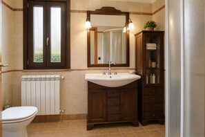 A bathroom with a white toilet, a white sink with a mirror above it, and a wooden cabinet with drawers. - Villa in Monterosso Almo with 3 bedrooms sleeps 8 (Monterosso Almo)