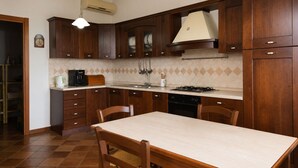 Une cuisine avec des meubles de rangement en bois, une cuisinière à gaz, un évier et une table à manger avec des chaises.